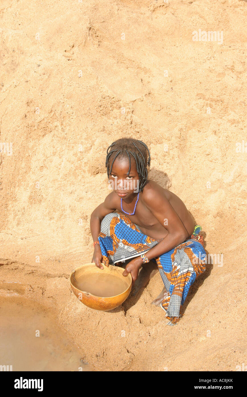 Young girl collecting dirty drinking water from a sandy dry river bed, Burkina Faso, West Africa Stock Photo