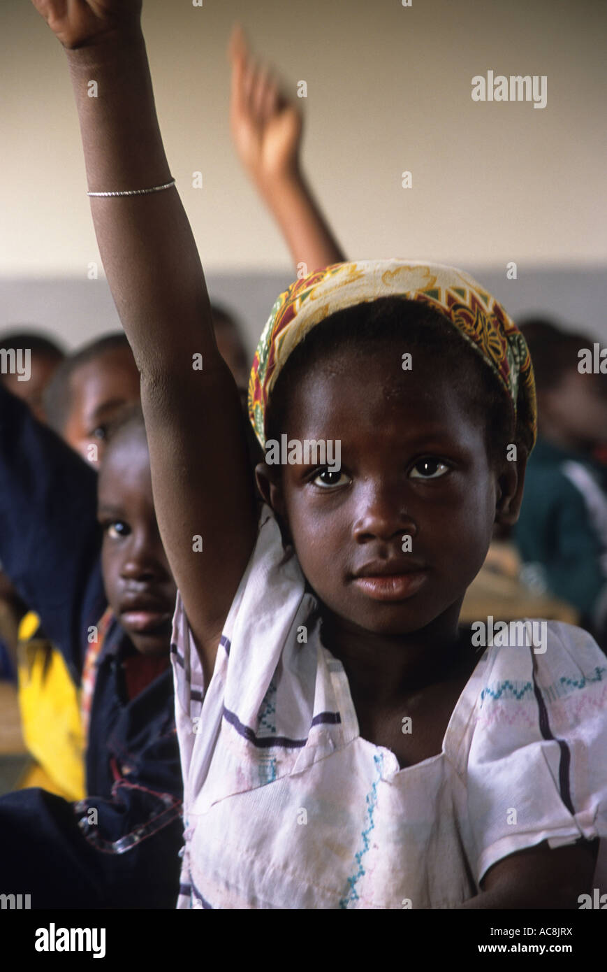 A young girl puts her hand up during a lesson at school, Mali, West