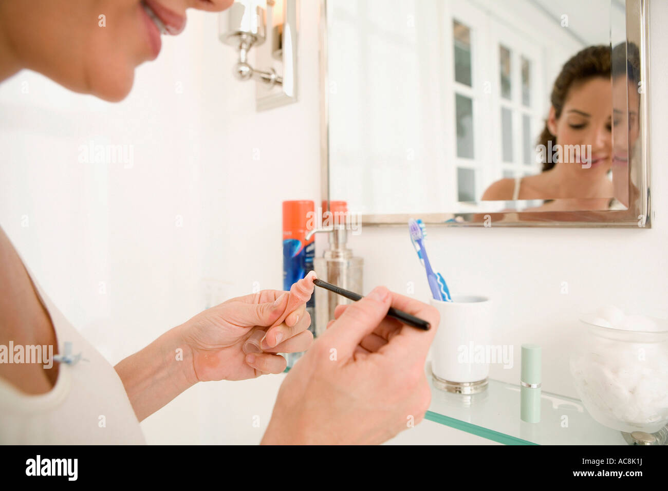 Close-up of a mid adult woman applying lip gloss to a make-up brush Stock Photo
