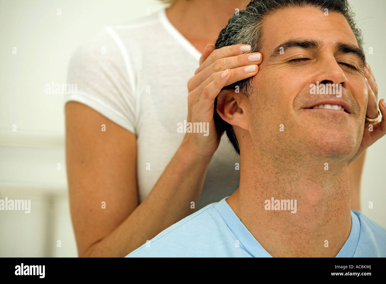 Mid adult woman massaging the temples of a mature man Stock Photo