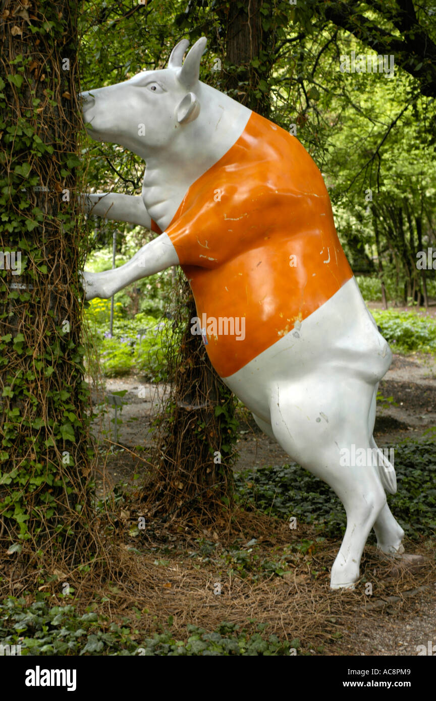 White Orange Cow Plastic Monument From Famous Cow Parade Is Supporting Tree From Falling Stock 