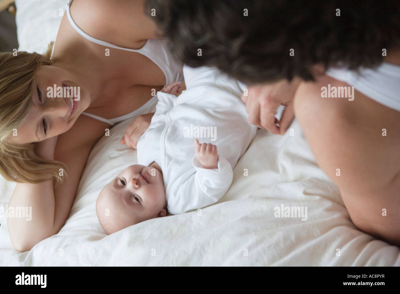 High angle view of a mid adult couple lying in bed with their baby ...
