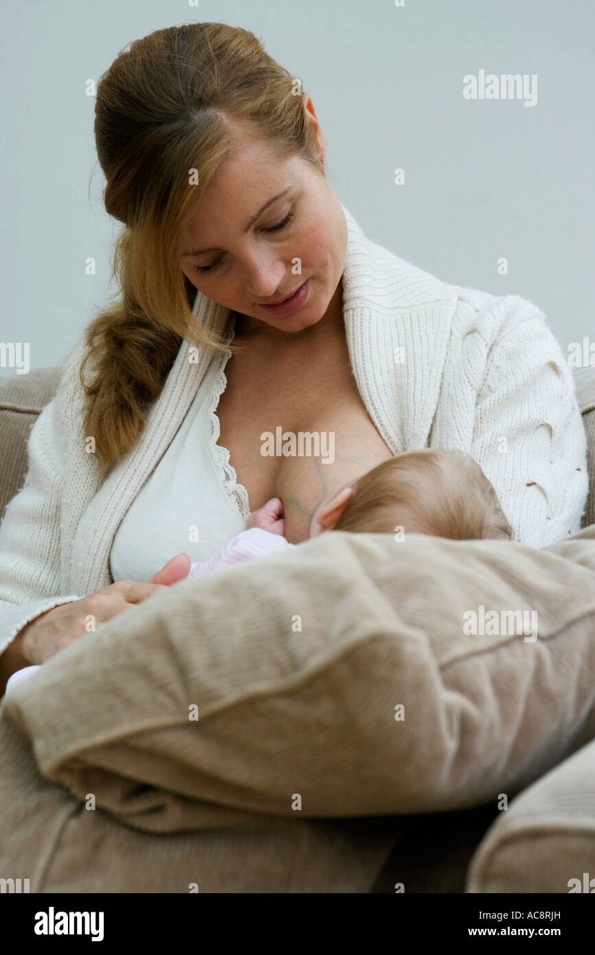 Mid adult woman breastfeeding her baby Stock Photo - Alamy