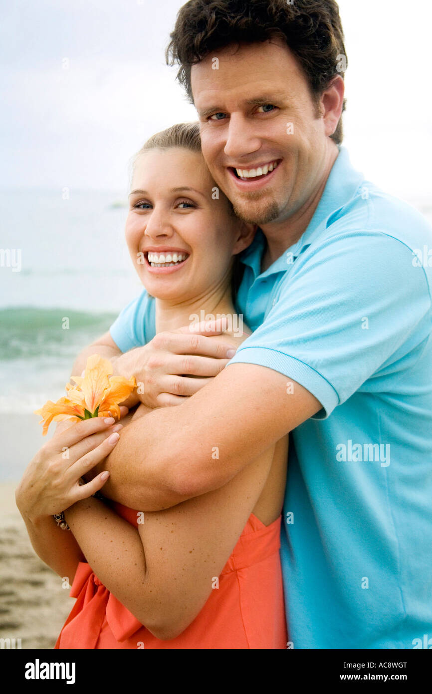 Mid adult man embracing a young woman from behind on the beach Stock ...