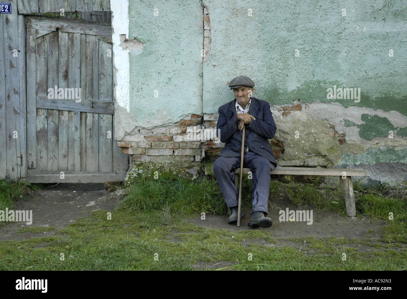 old man sitting on a bench, Viscri Stock Photo