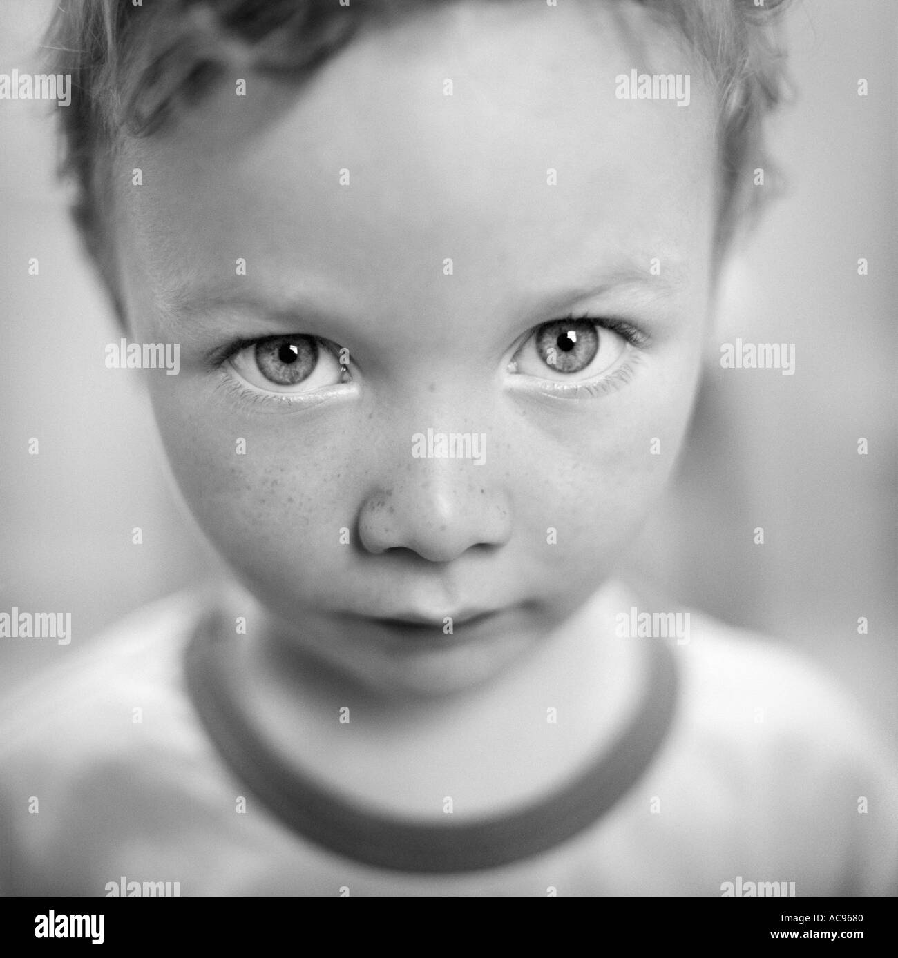 white boy with freckled skin looking at the camera aged four with intense gaze Stock Photo