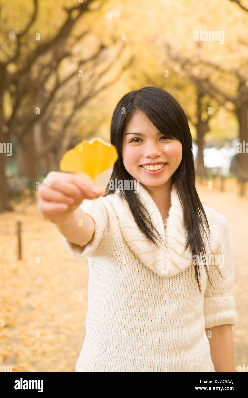 Young woman holding yellow ginkgo leaf Stock Photo