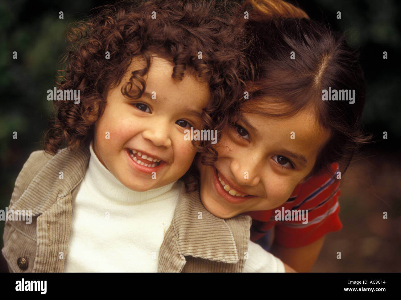 Two little girls leaning in close looking at the camera smiling Stock ...