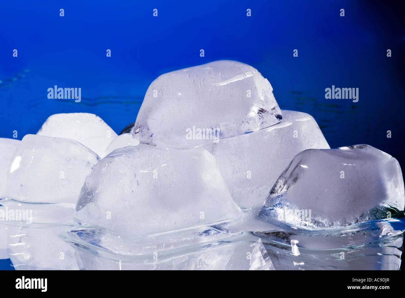 Melting ice cube with water drops on a mirror - blue background Stock ...