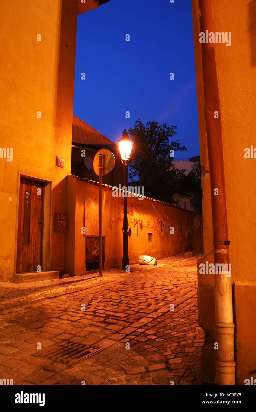 Illuminated cobblestone alley with a street lamp and graffiti in Prague ...