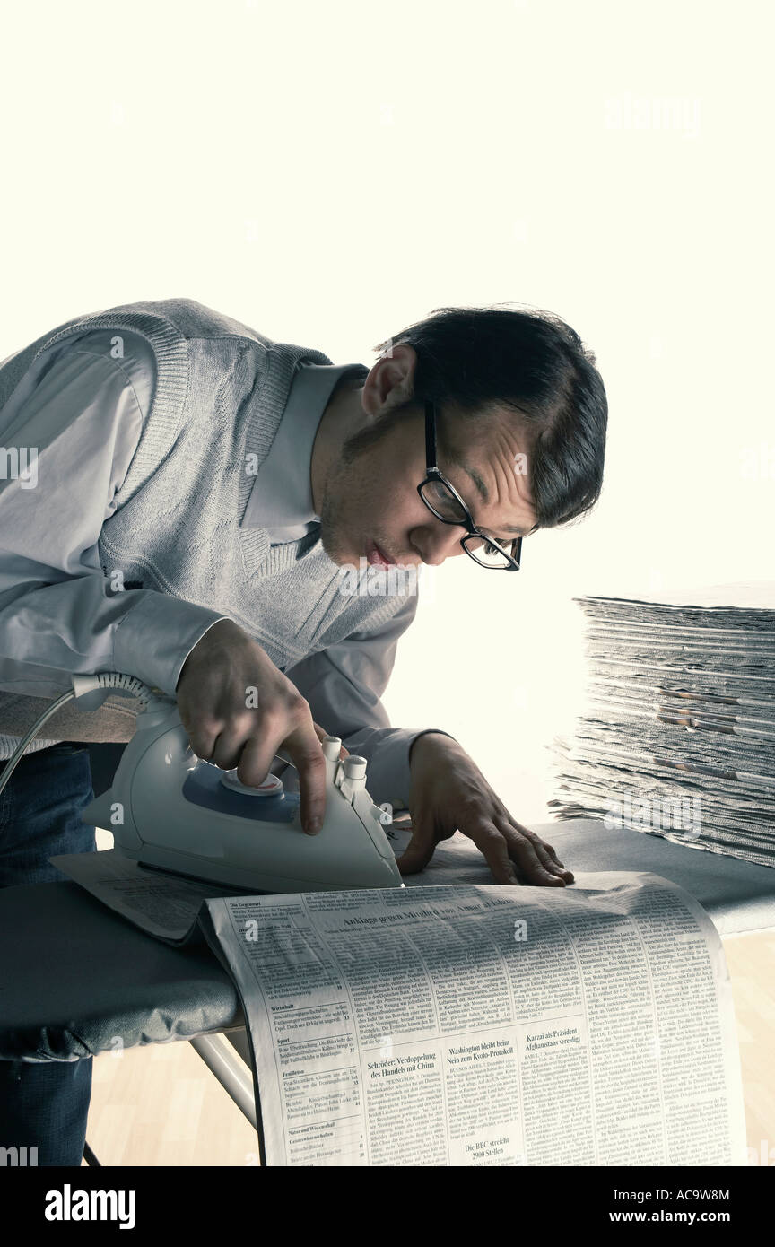 Critical young man ironing newspapers Stock Photo Alamy