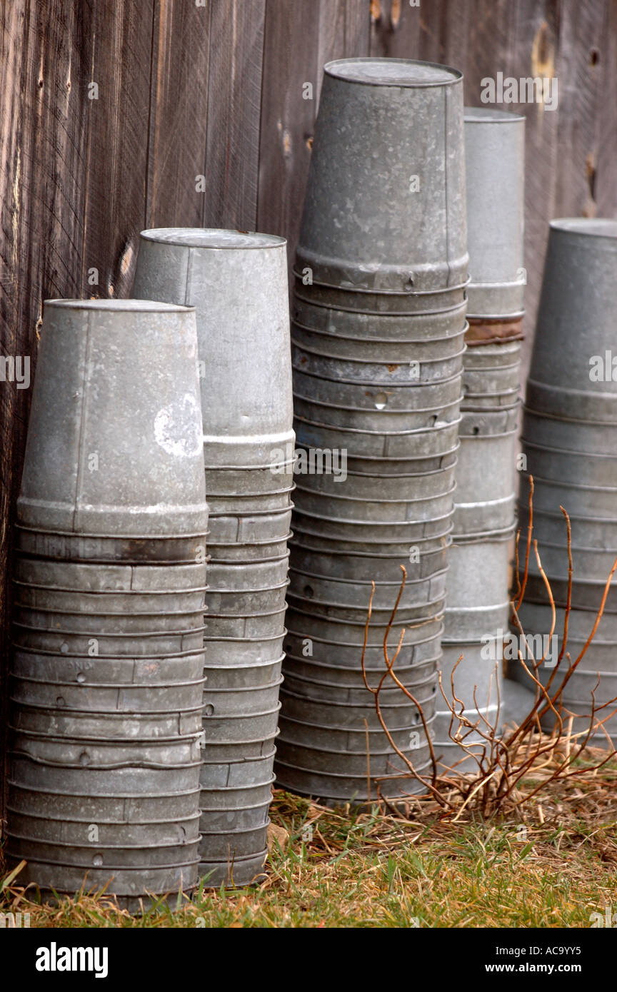 pails buckets stacked upside down tin maple syrup farm holding piled barn late winter harvest stacks bucket pail rows columns co Stock Photo