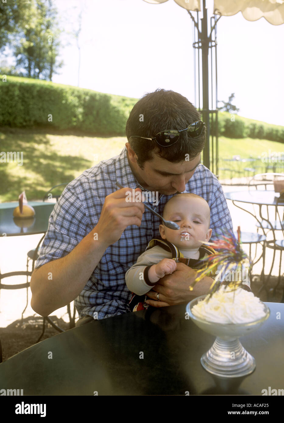 Father feeding his baby son ice cream at a cafe outdoors on holiday in France. Stock Photo