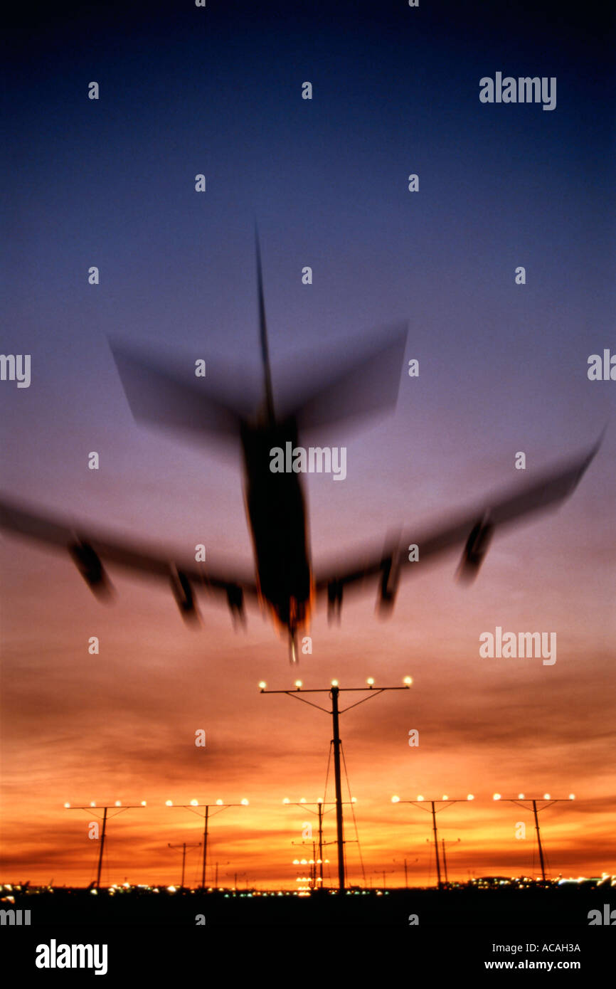 Boeing 747 jumbo jet landing at sunset sunrise dusk night over runway landing approach lights Stock Photo