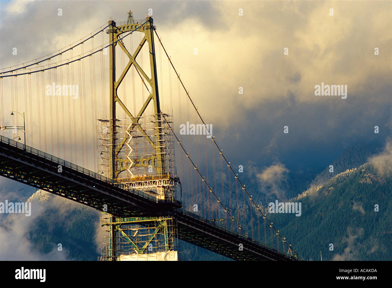 Lions Gate Bridge in golden light with clouds and snow dusted hills, Vancouver, British Columbia, Canada Stock Photo