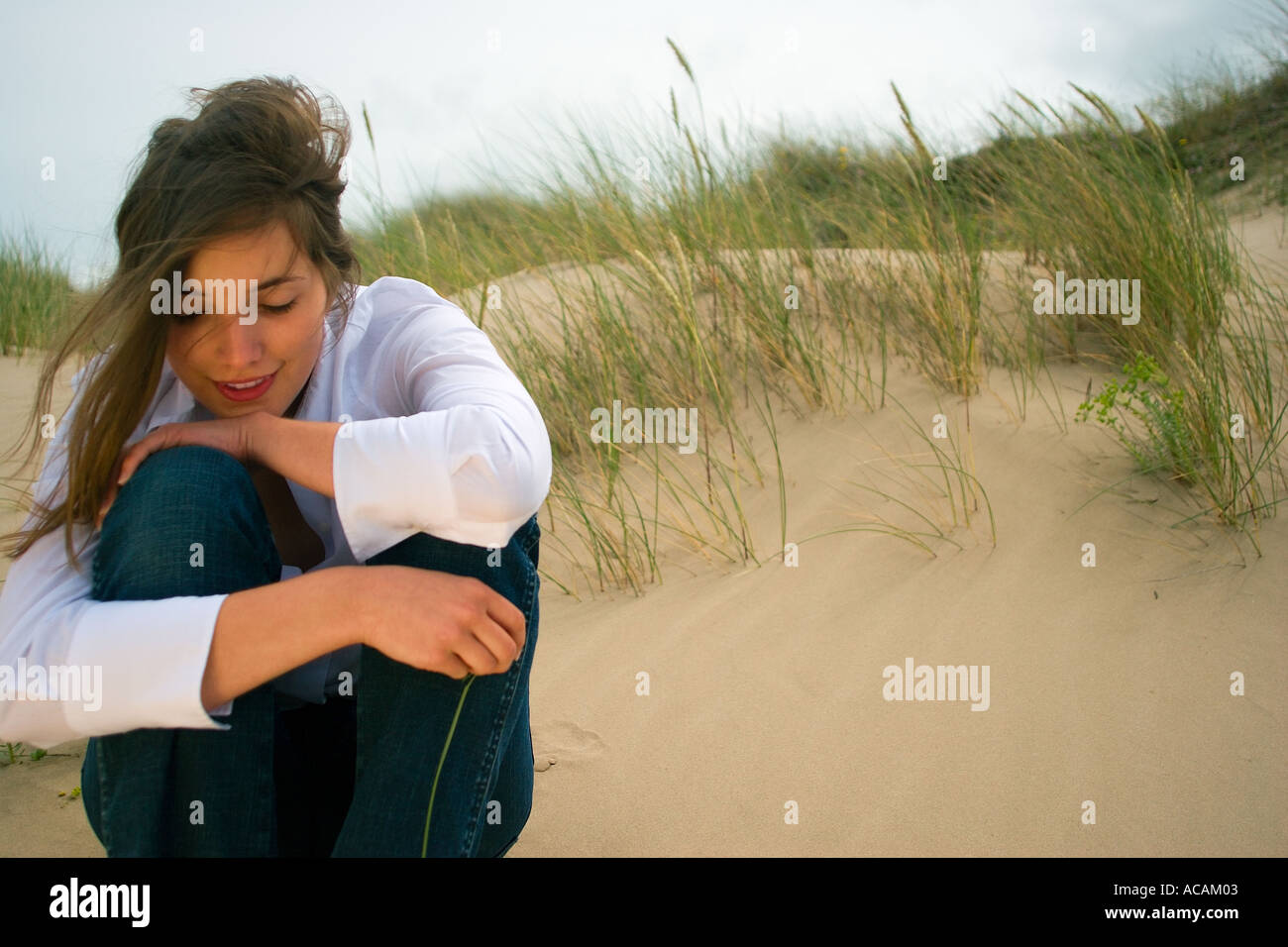 Young woman sitting on dunes Stock Photo - Alamy