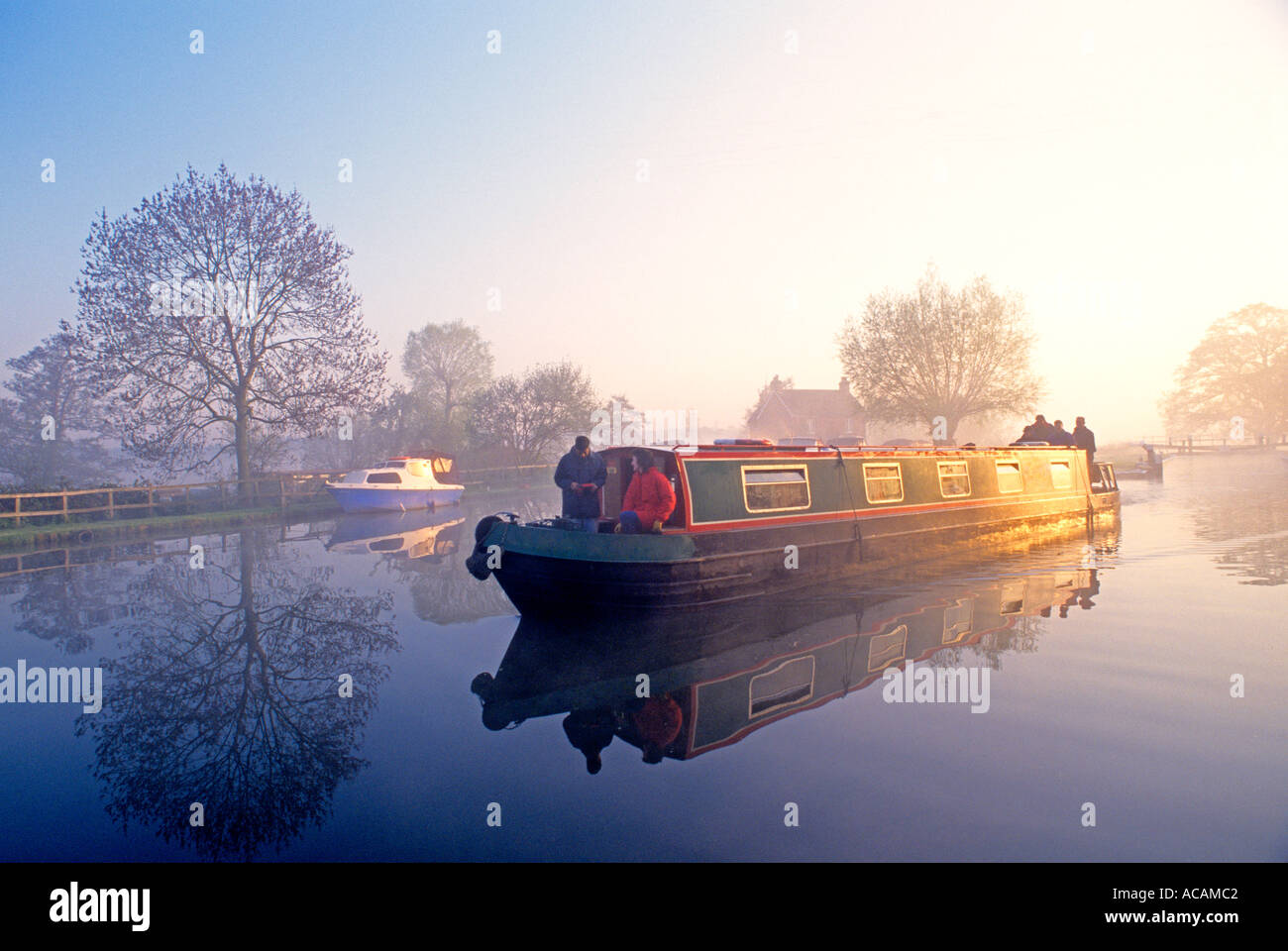 Staycation River Wey Traditional holiday hire narrowboat leaving Papercourt Lock on a misty still summer autumn sunrise River Wey Surrey England UK Stock Photo