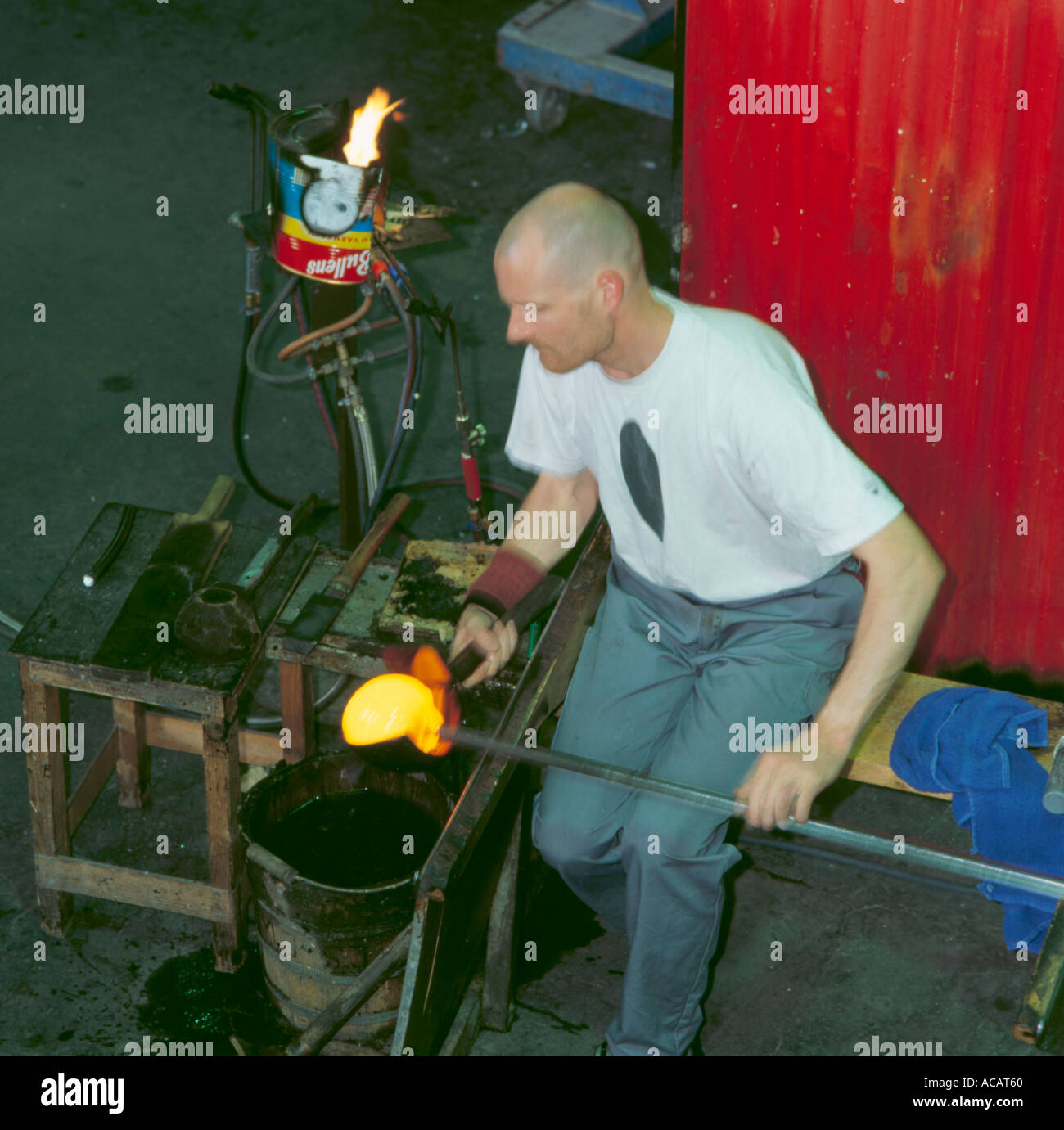 Glass maker working hot semimolten glass at a glass works, Orrefors