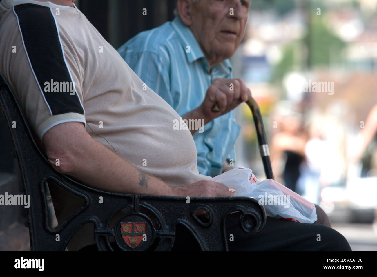 Two older men on a bench one with a large belly Stock Photo