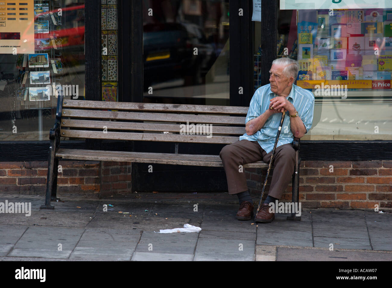 Old man sitting alone on a bench in the town of Colchester Essex England Stock Photo