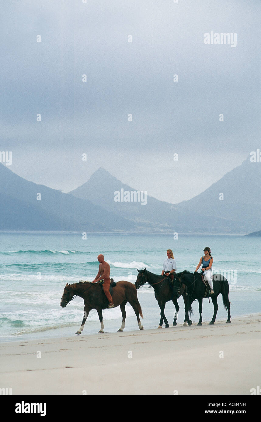 Three Horse Ridiers on Noordhoek Beach Hout Bay in background Cape Town South Africa Stock Photo