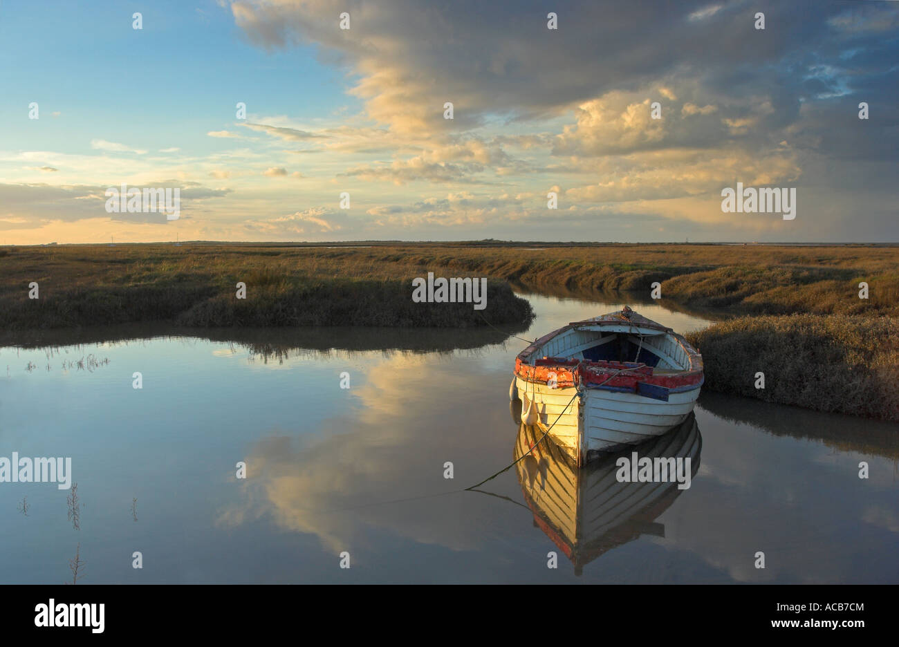 An old and worn wooden rowing boat in a saltmarsh creek at Burnham