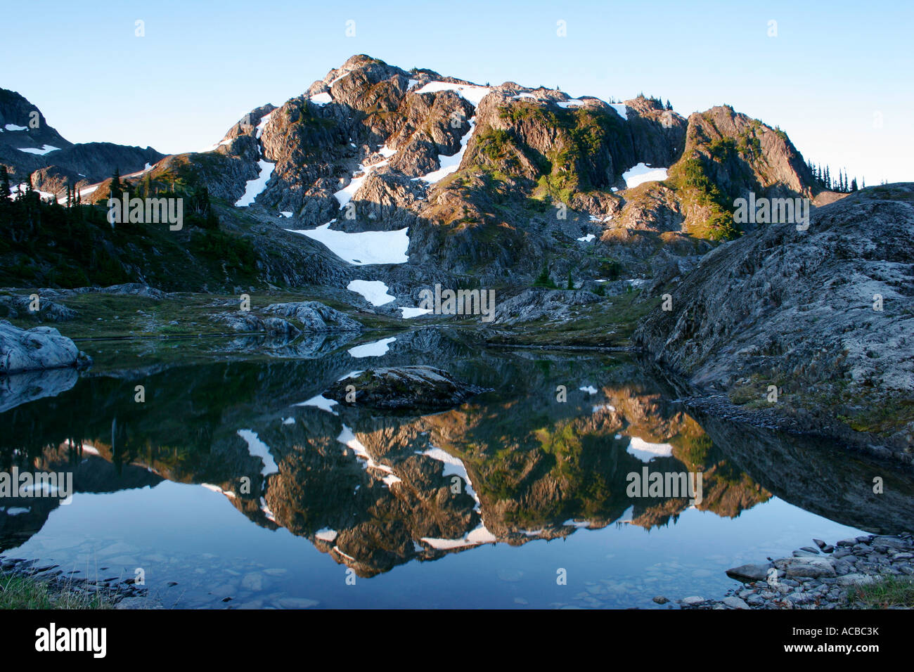 Early light on a peak in Ferry Basin is reflected in a tarn Bailey ...