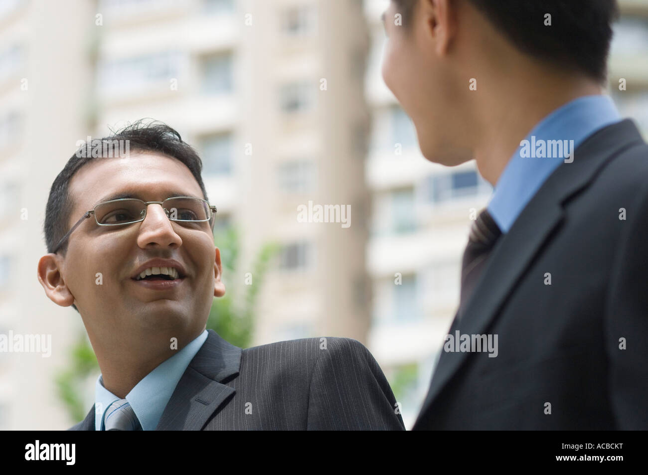 Two businessmen looking at each other and smiling Stock Photo - Alamy