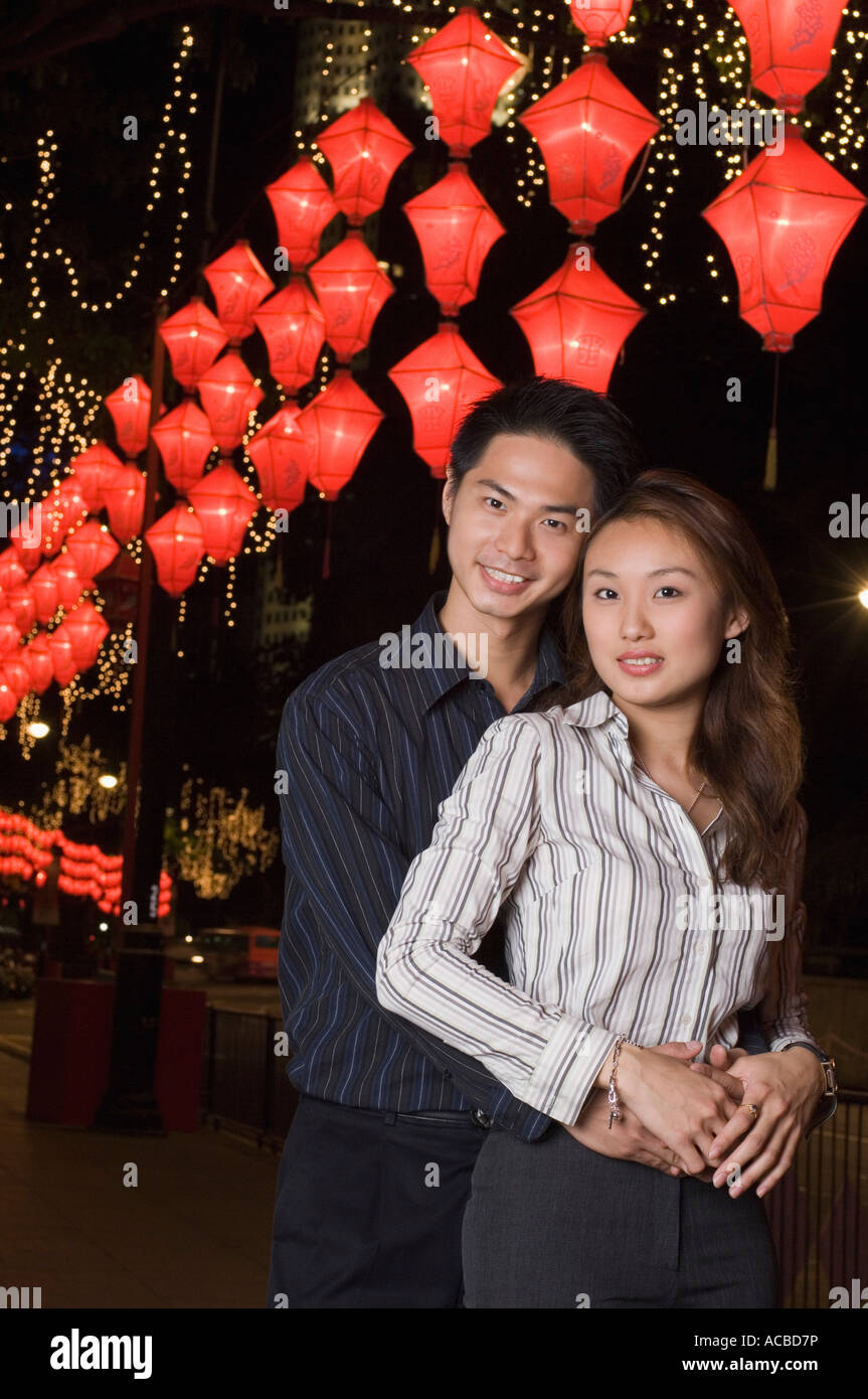 Portrait of a young man embracing a young woman from behind Stock Photo ...