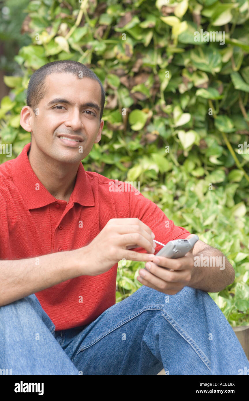 Portrait of a young man operating a mobile phone with a digitized pen Stock Photo