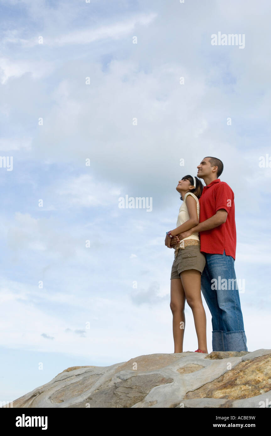 Low angle view of a young man embracing a mid adult woman from behind ...