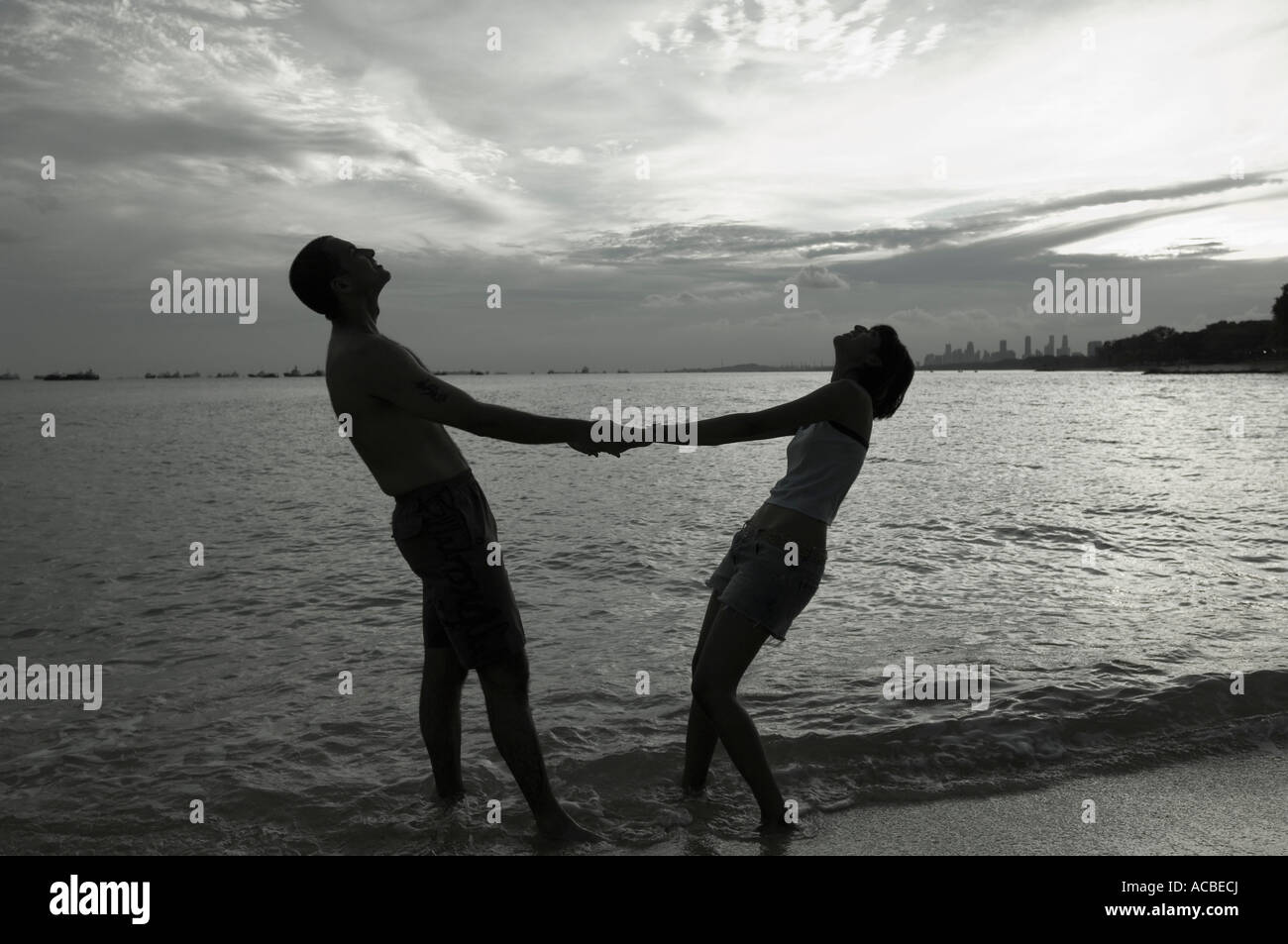Silhouette of a couple holding hands and standing on the beach Stock ...