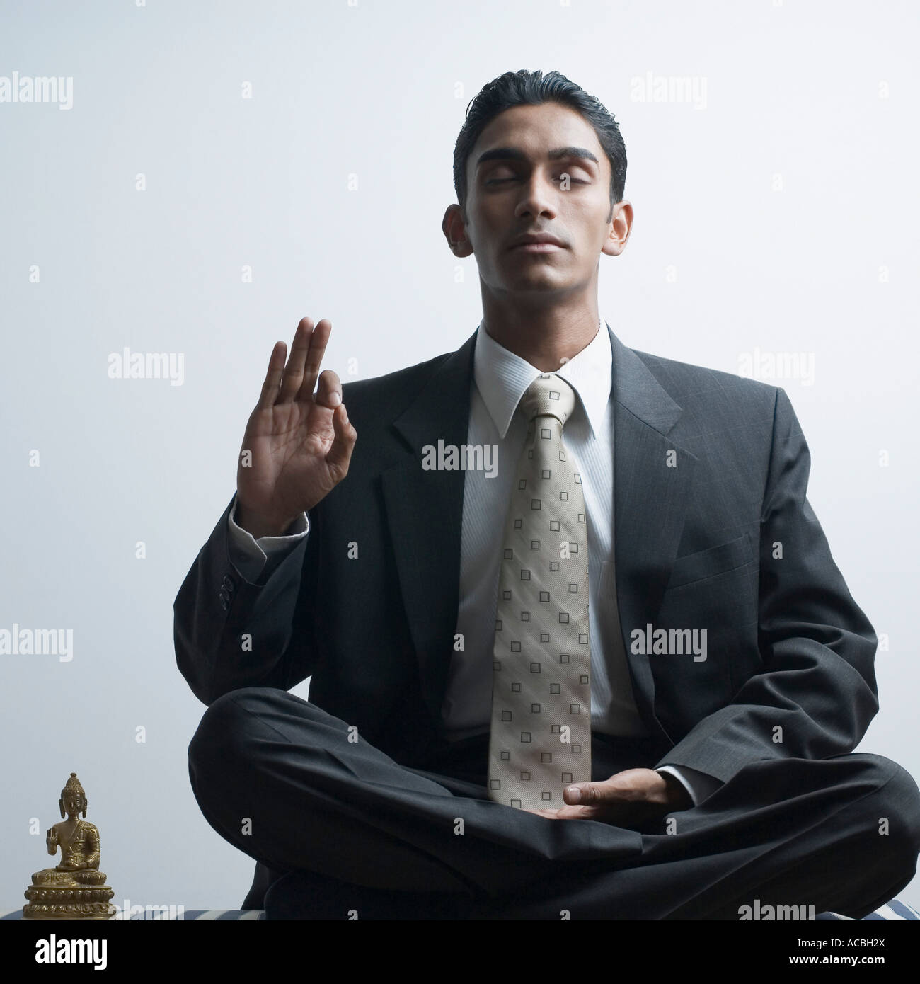 Businessman meditating beside a Buddha statue Stock Photo - Alamy