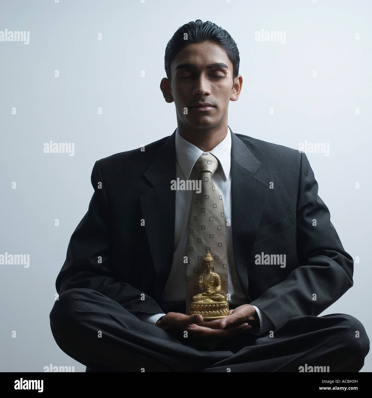 Businessman meditating beside a Buddha statue Stock Photo - Alamy