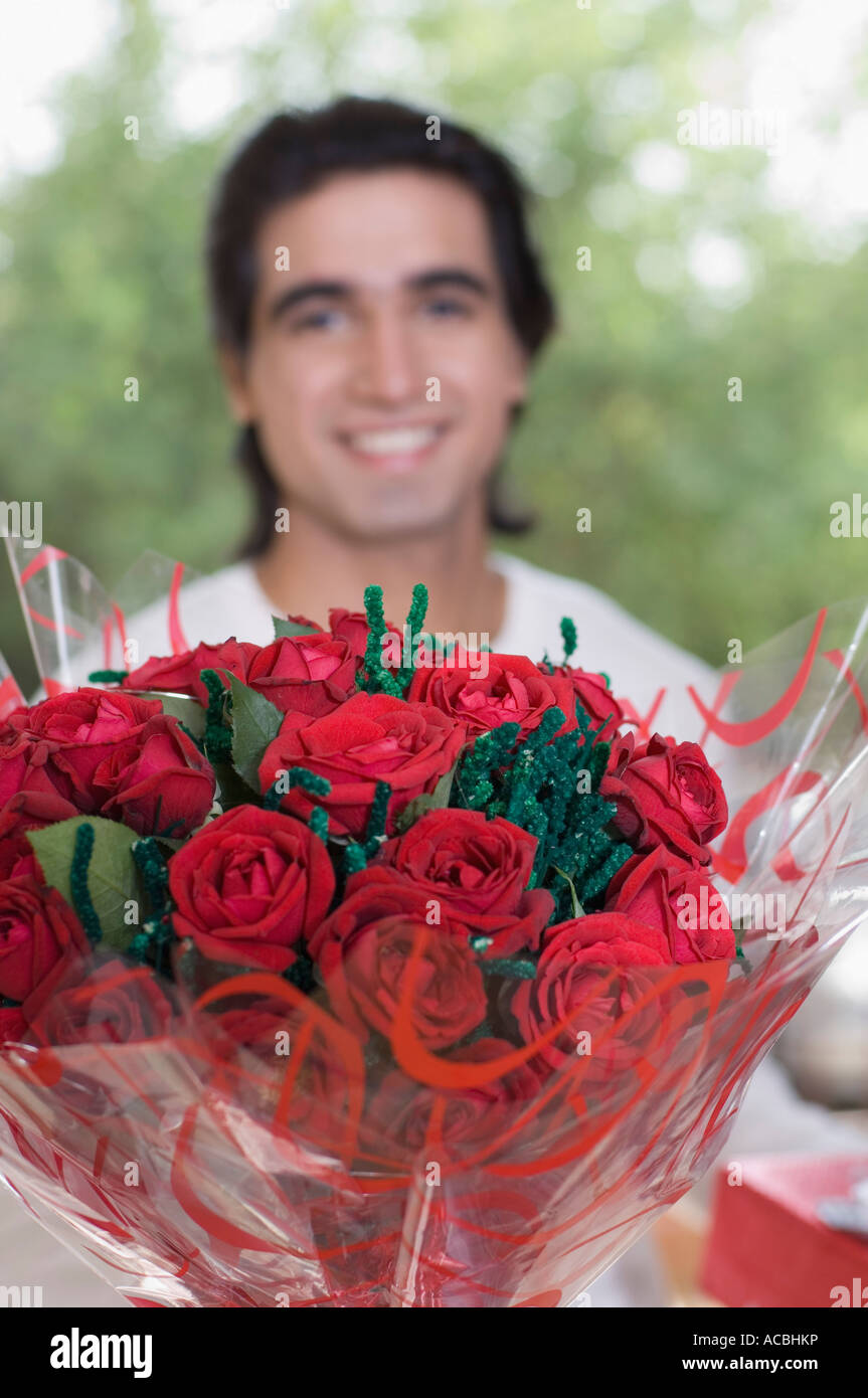 Close-up of a bouquet of flowers with a young man smiling in the ...