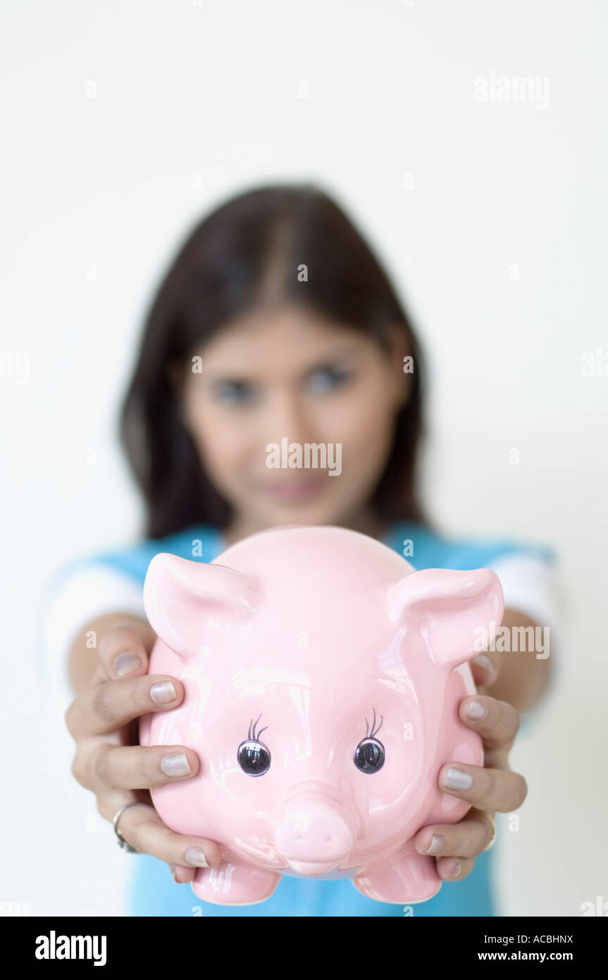 Portrait of a young woman holding a piggy bank Stock Photo - Alamy