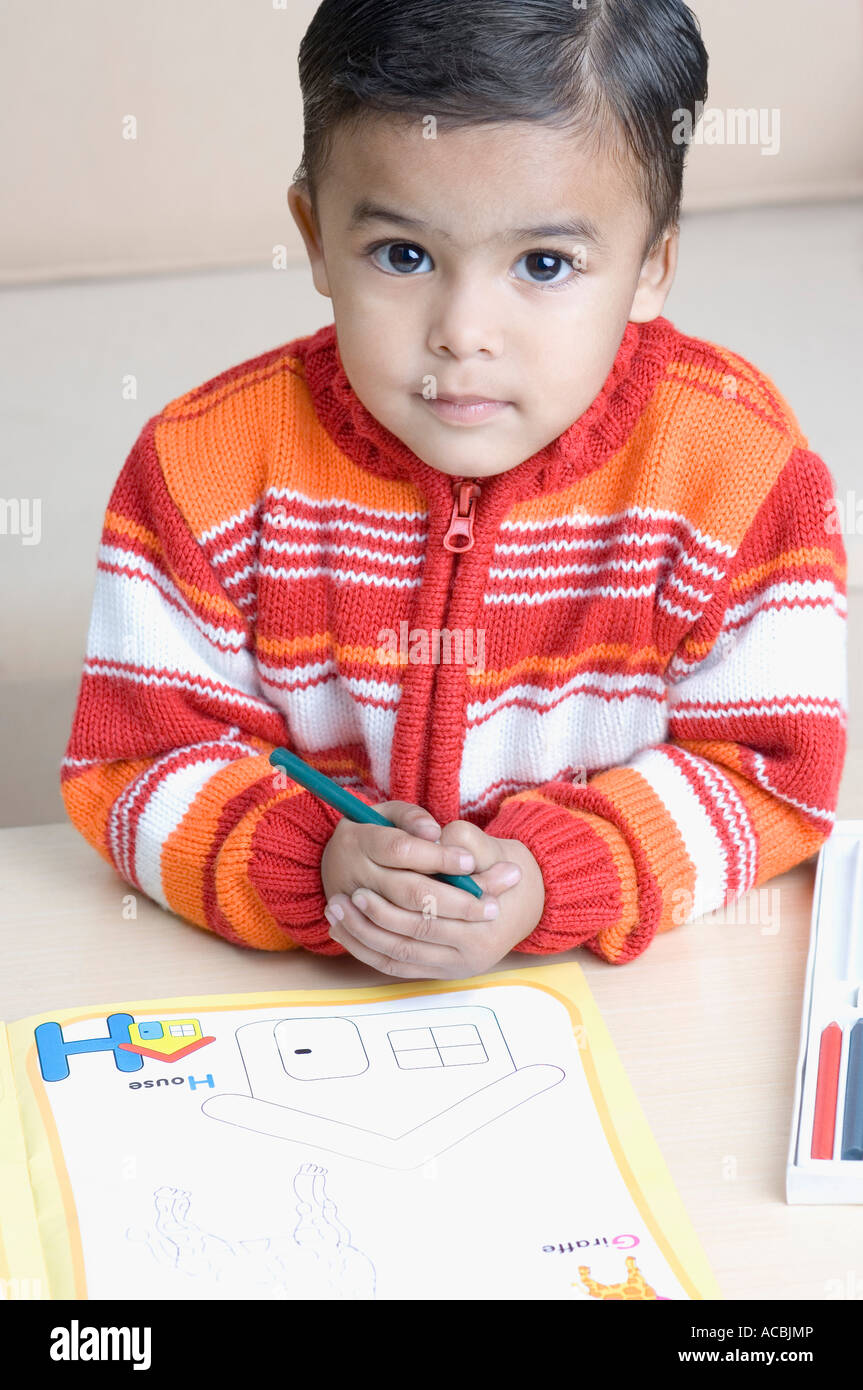 High angle view of a boy holding a crayon near a coloring book Stock Photo