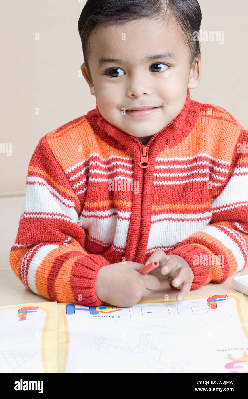 Close-up of a boy smiling and holding a crayon Stock Photo