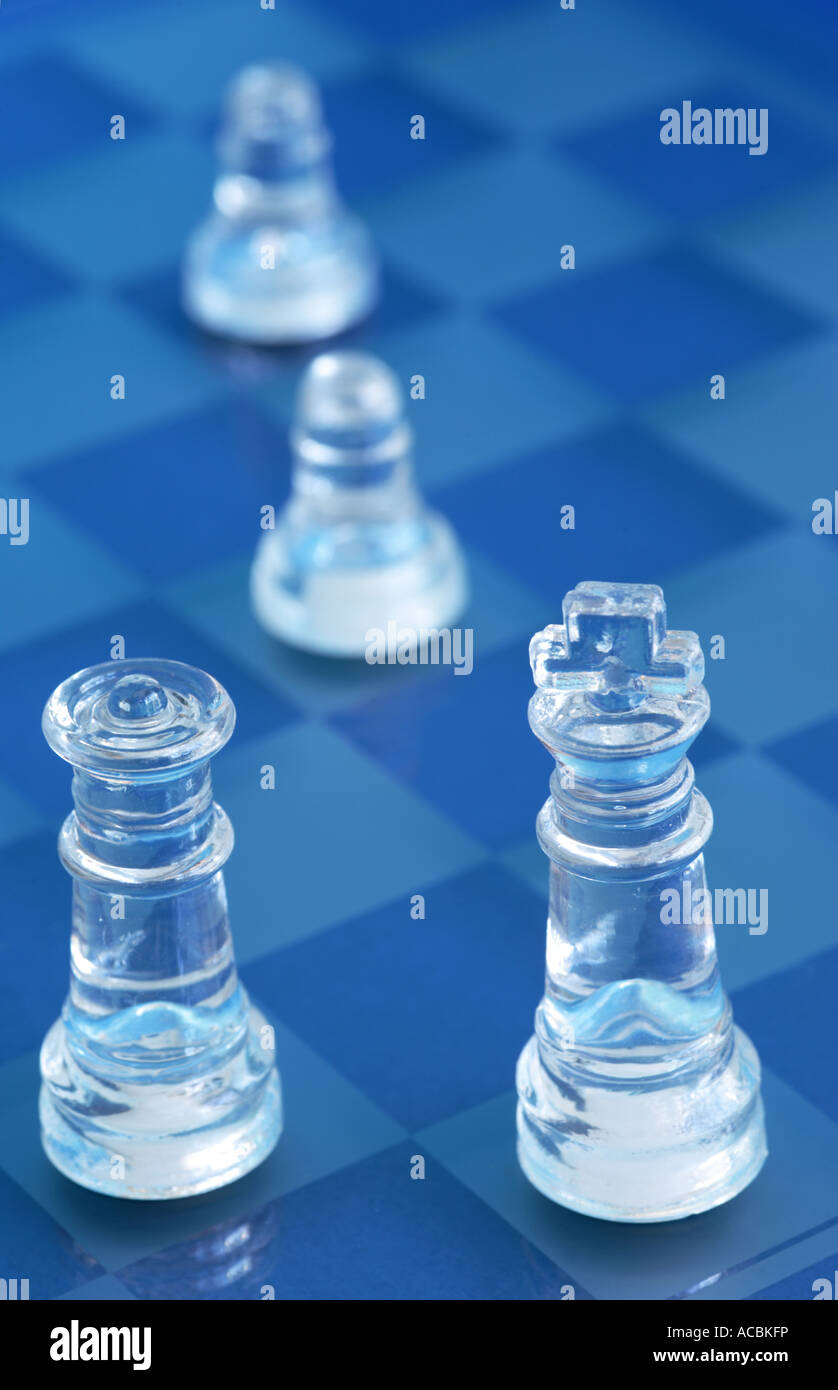 Glass chess pieces on blue glass board Stock Photo