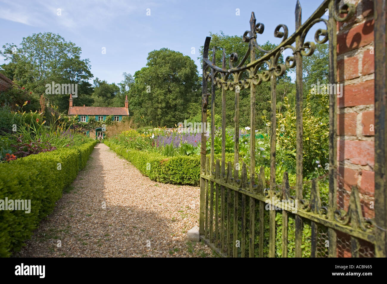 Path Leading Through Gate To Old Cottage In Walled English Country