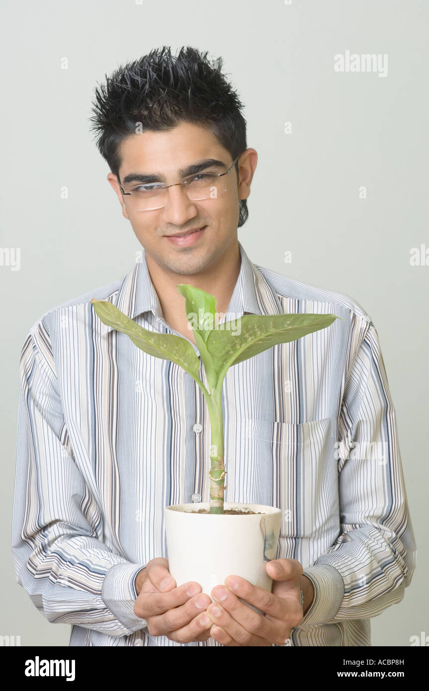 Portrait of a young man holding a potted plant Stock Photo - Alamy