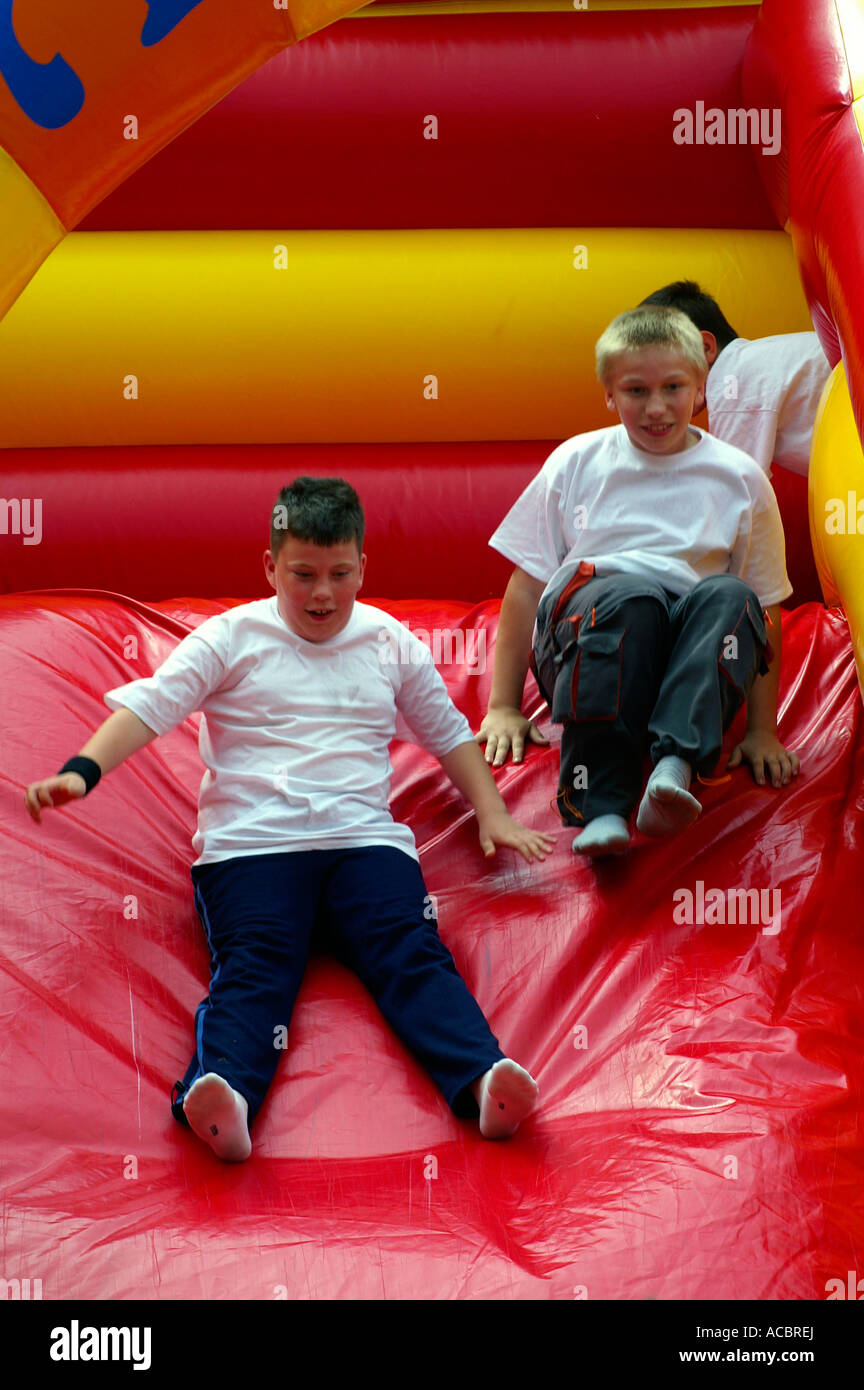 Two boys sliding on inflatable red slide Stock Photo - Alamy