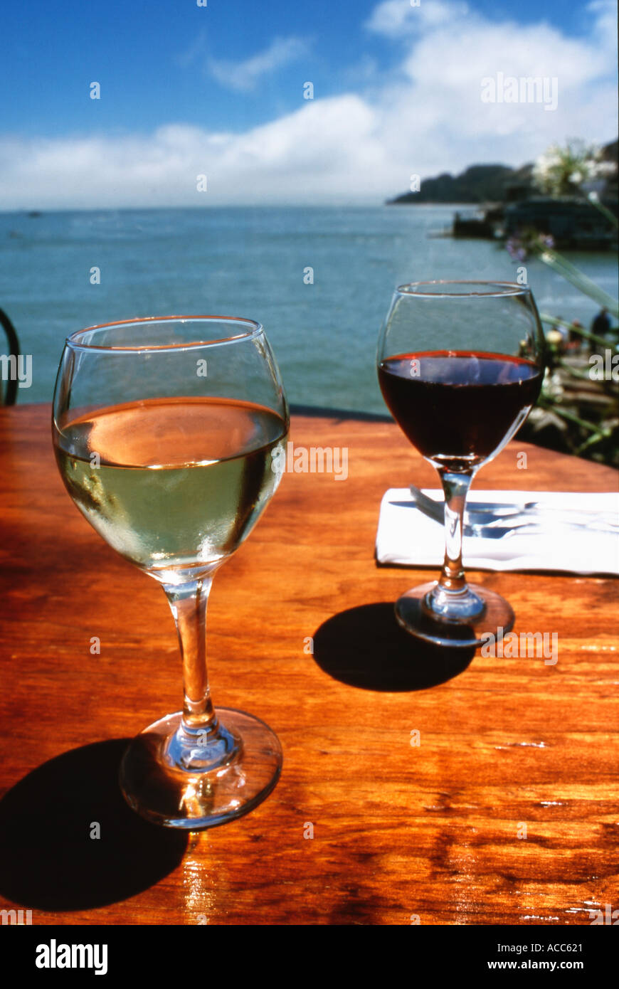 Glasses of red and white wine sitting on a wood table in an outdoor ...