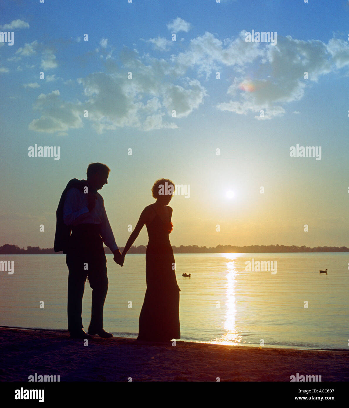 young couple walking on beach at sunset Stock Photo