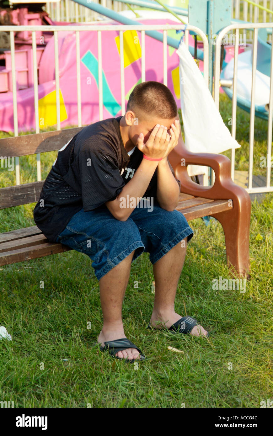Boy sitting on bench with head in hands Stock Photo