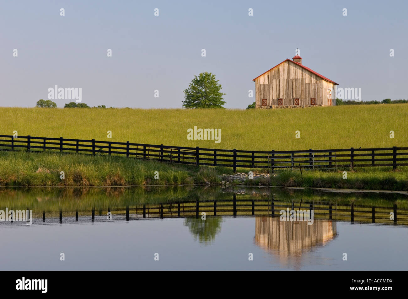 Black Wood Fence Pasture and Barn Reflecting in Pond Near Starlight Indiana Stock Photo