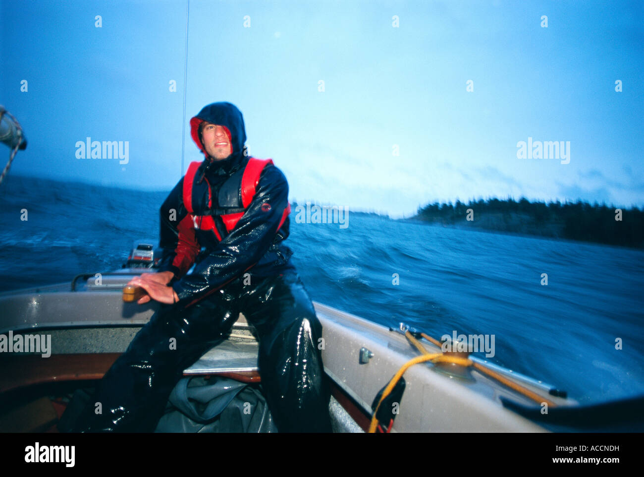 A man in rain clothes in a motorboat Stock Photo - Alamy
