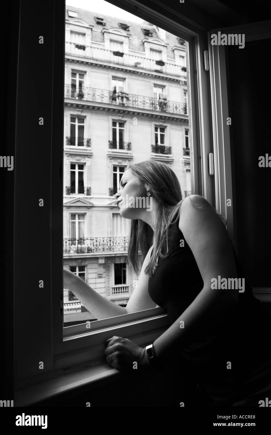 Black and white photo of a young woman yelling out a window in Paris, France Stock Photo