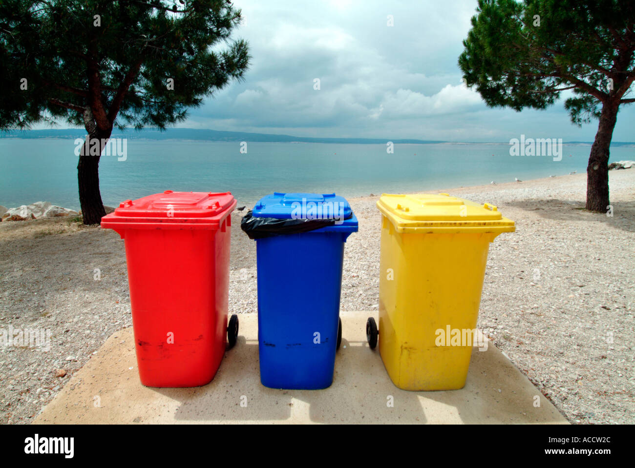 yellow red and blue dustbin on a beach Stock Photo