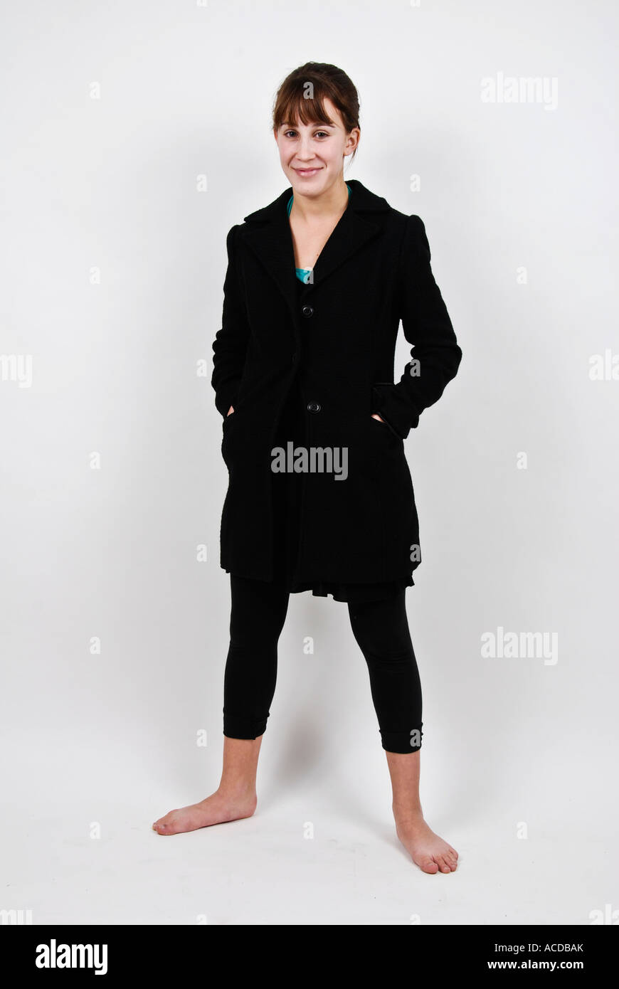 Cute teenage girl without shoes standing against a white background in